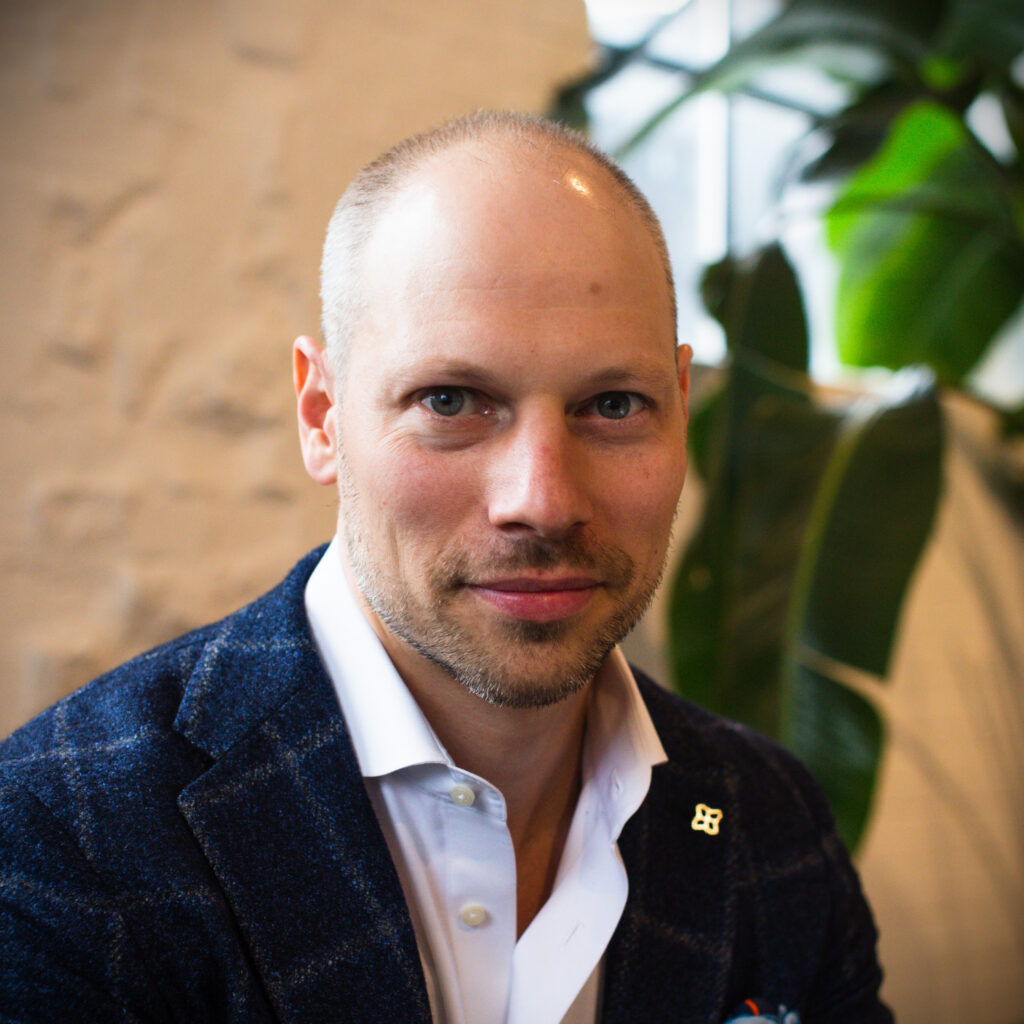 Professional headshot of Rowan Cainer, VP of Growth at ClearSight Health, in blazer with plant in background